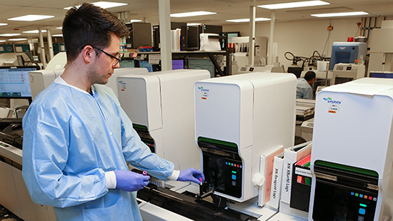Man placing a vial into an lab instrument